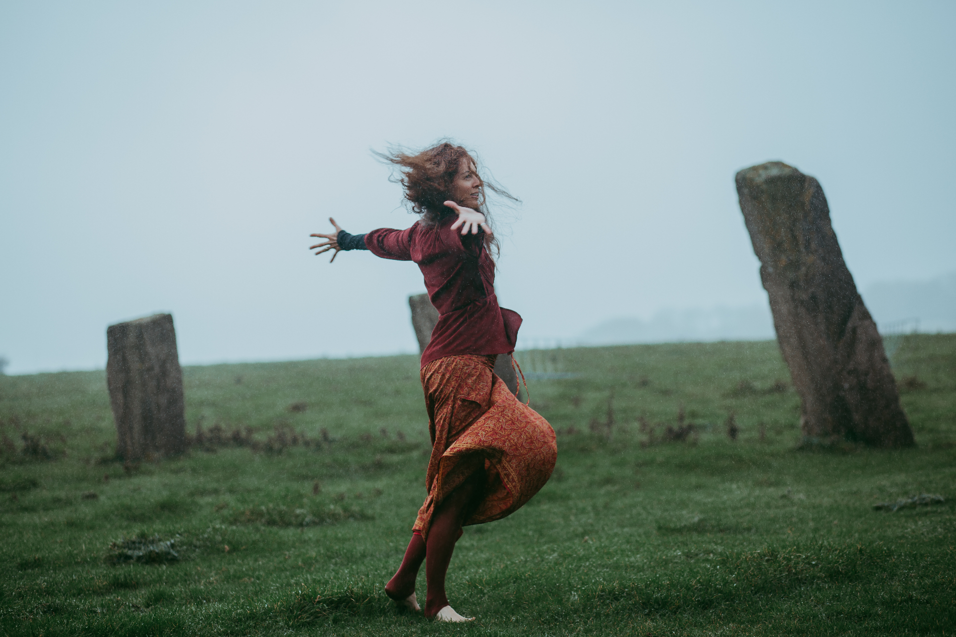 A woman moving freely in the Scottish mist among ancient stones